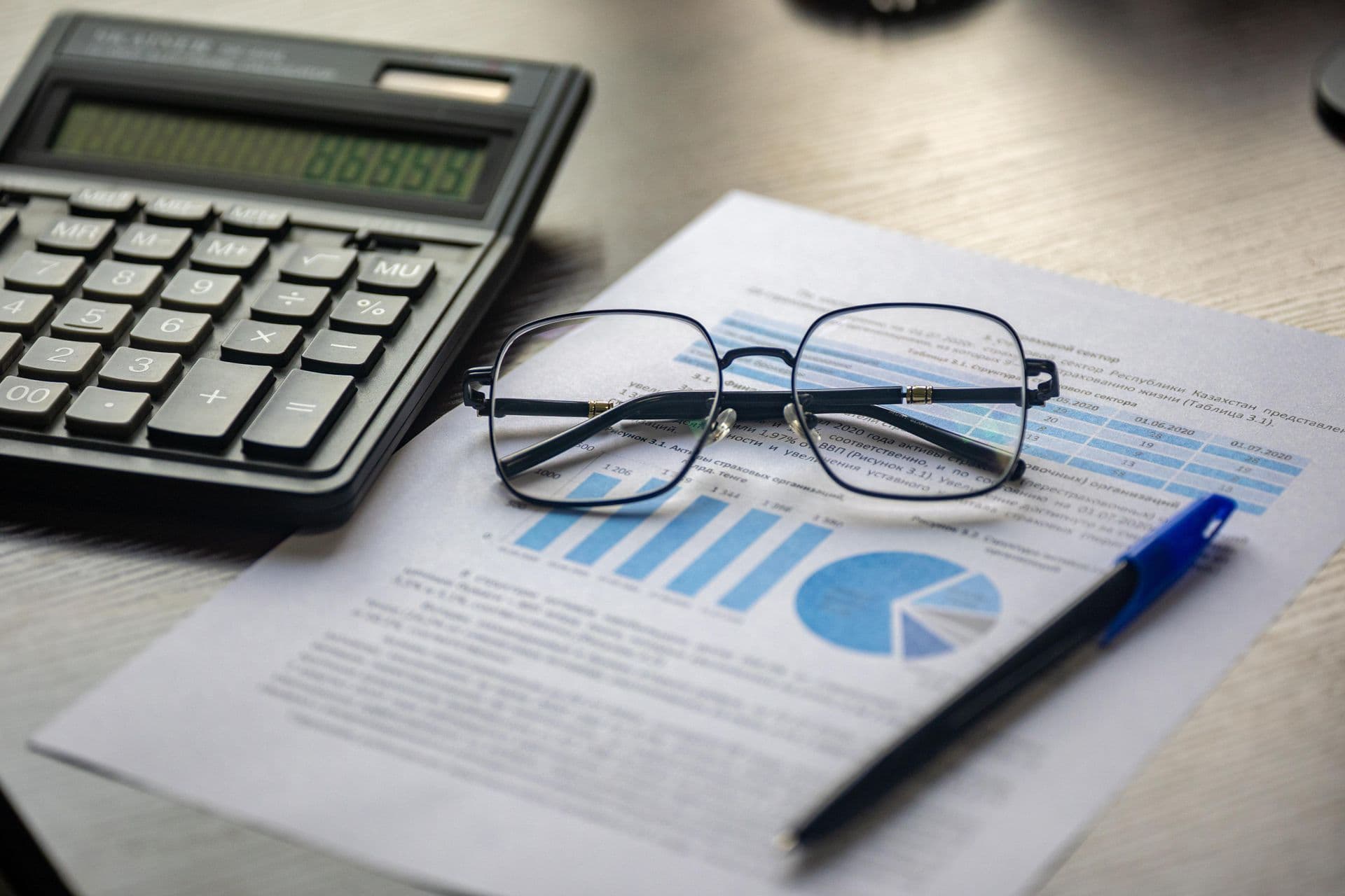 Lunettes et calculatrice posées sur des rapports d’analyse