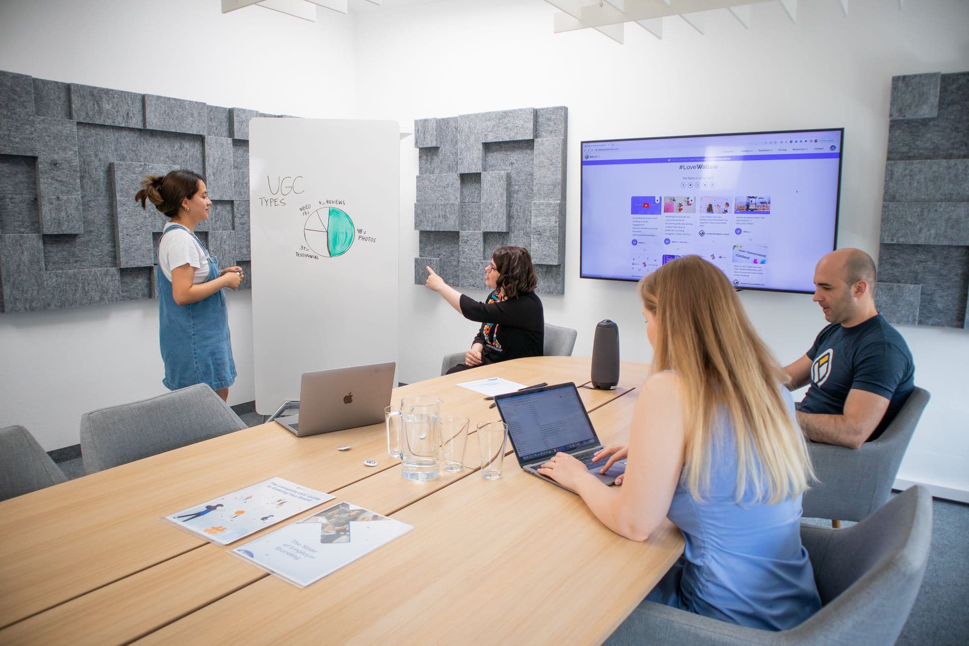 Équipe en réunion devant un tableau et un écran de présentation